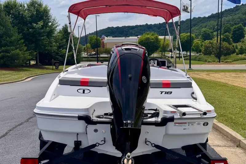 Slide: The Image of 2026 Tahoe T18 boat with red canopy and outboard motor, parked outdoors. - 11