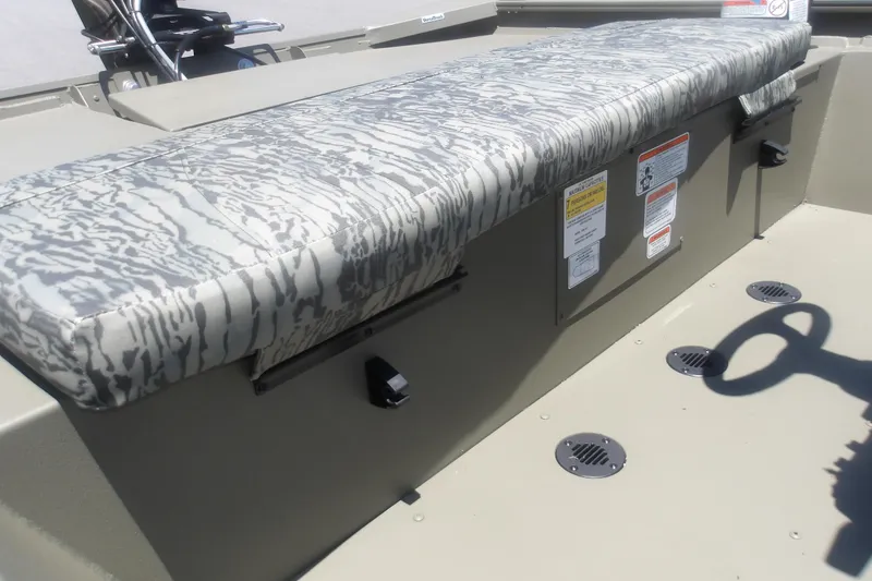 Slide: The Image of 2026 Tracker Grizzly 1860 CC boat interior with camo-patterned seating and safety labels. - 16
