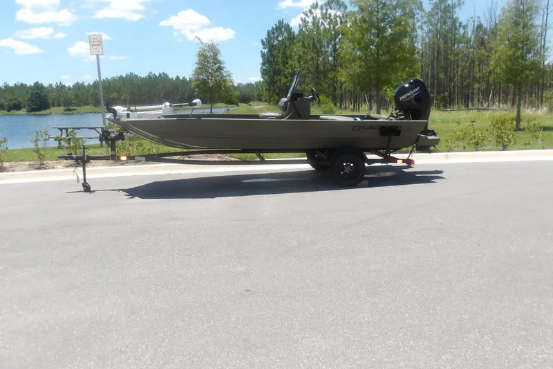 The Image of 2026 Tracker Grizzly 1860 CC boat on trailer by a scenic lake. - 1