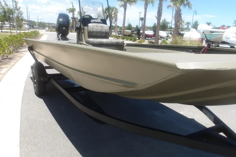 Slide: The Image of 2026 Tracker Grizzly 1860 CC boat on trailer, parked outdoors with palm trees in background. - 7
