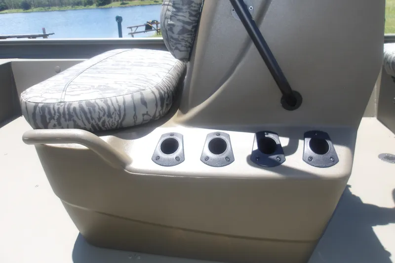 Slide: The Image of 2026 Tracker Grizzly 1860 CC boat seat with cup holders, near a serene lake. - 12
