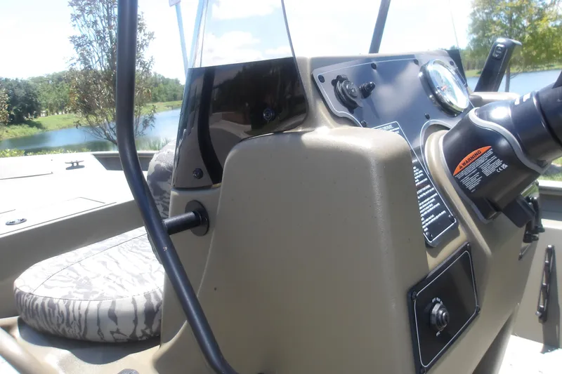 Slide: The Image of 2026 Tracker Grizzly 1860 CC boat console with steering wheel, gauges, and camouflage seat. - 14