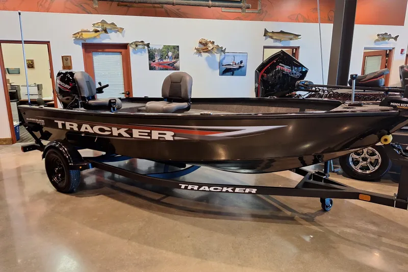 The Image of 2026 Tracker Super Guide V-16 T fishing boat displayed indoors on a trailer. - 0