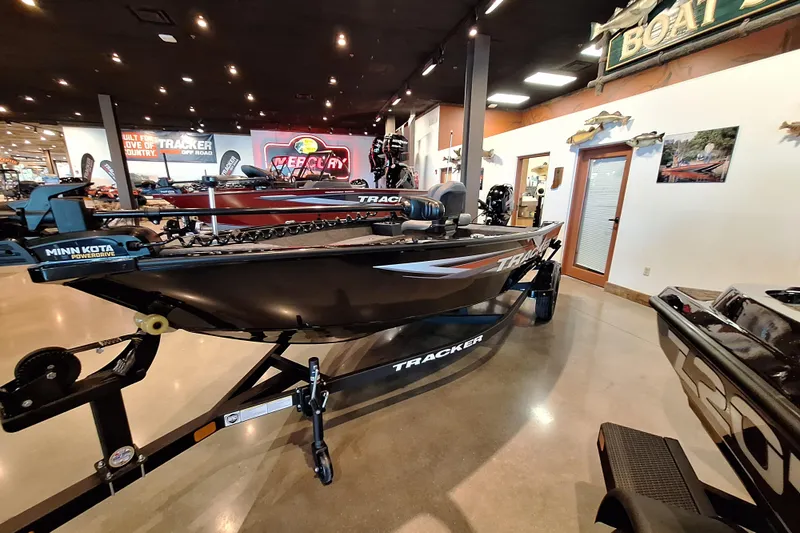 Slide: The Image of 2026 Tracker Super Guide V-16 T boat displayed in a showroom with Minn Kota PowerDrive. - 2