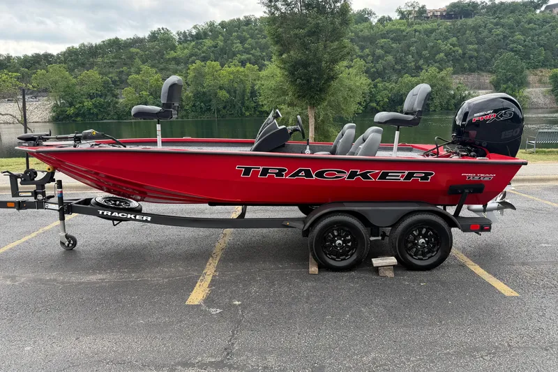 The Image of Red 2026 Tracker Pro Team 195 boat on trailer, parked near a scenic lake. - 0