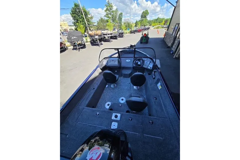 Slide: The Image of 2026 Tracker Pro Guide V-175 WT boat interior with seating and steering wheel, parked outdoors. - 58