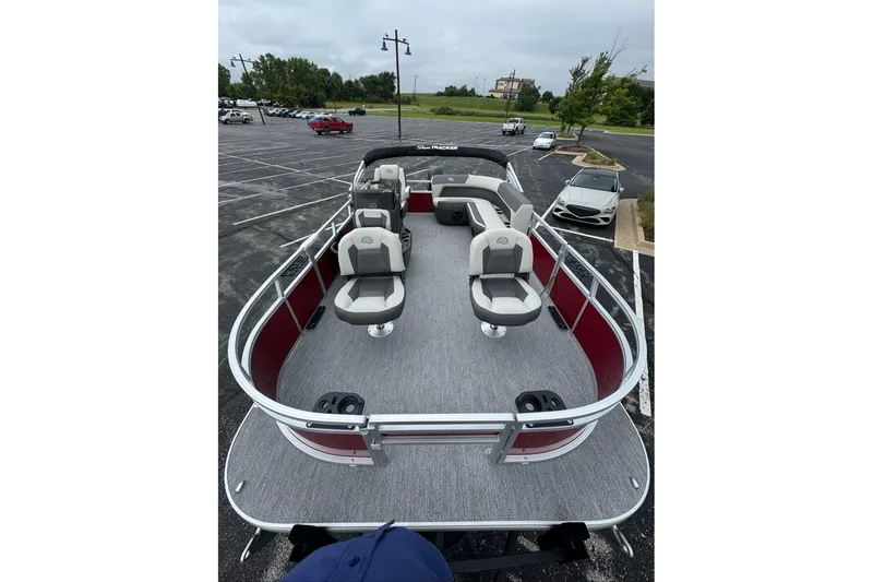 Slide: The Image of 2026 Sun Tracker Bass Buggy 16 XL Select pontoon boat with spacious seating in a parking lot. - 12