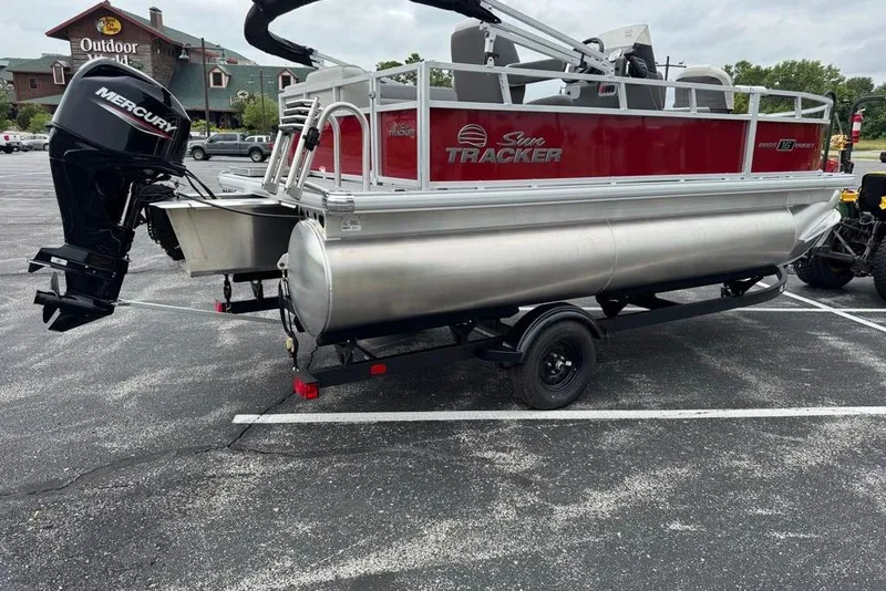 Slide: The Image of 2026 Sun Tracker Bass Buggy 16 XL Select pontoon boat with Mercury engine in parking lot. - 2