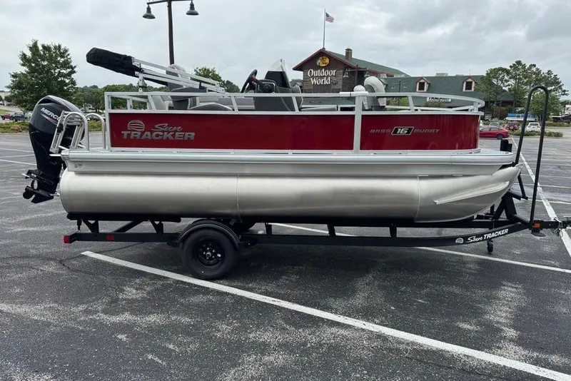 Slide: The Image of 2026 Sun Tracker Bass Buggy 16 XL Select pontoon boat on trailer in parking lot. - 3