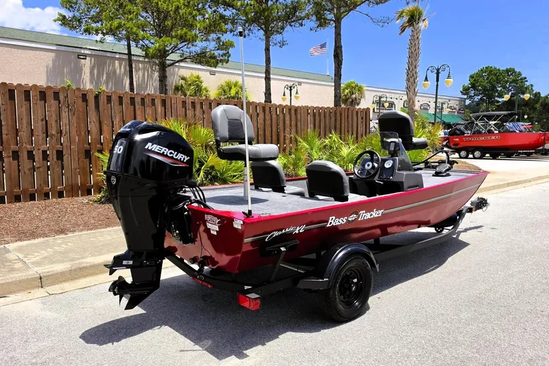 Slide: The Image of 2026 Tracker Bass Tracker Classic XL boat with Mercury engine, parked outdoors on a sunny day. - 2