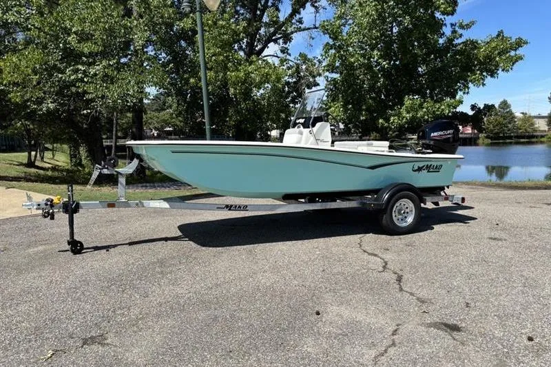 Slide: The Image of 2026 Mako Pro Skiff 15 CC boat on trailer, parked near a scenic lake. - 12