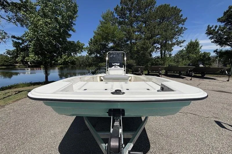 Slide: The Image of 2026 Mako Pro Skiff 15 CC boat on trailer, parked near a scenic lake. - 5