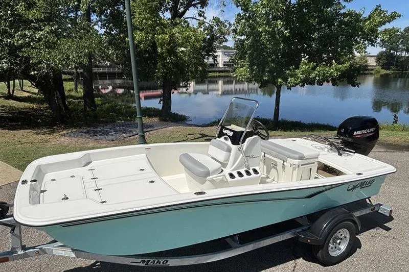 Slide: The Image of 2026 Mako Pro Skiff 15 CC boat on trailer by a scenic lake. - 67