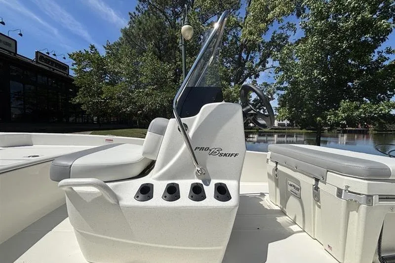 Slide: The Image of 2026 Mako Pro Skiff 15 CC boat interior with console and seating by a lake. - 9