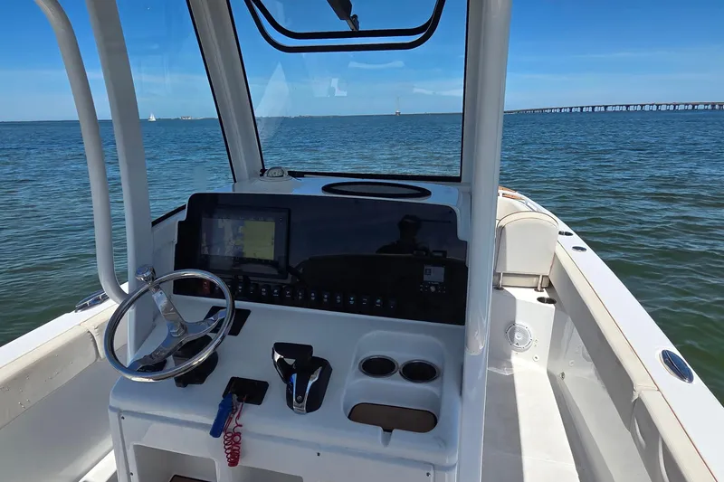 Slide: The Image of 2021 Sea Hunt Escape 27 boat dashboard with steering wheel, controls, and ocean view. - 14