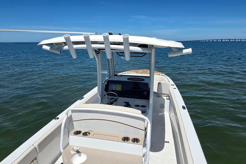 Slide: The Image of 2021 Sea Hunt Escape 27 boat on calm water, featuring a sleek console and rod holders. - 16