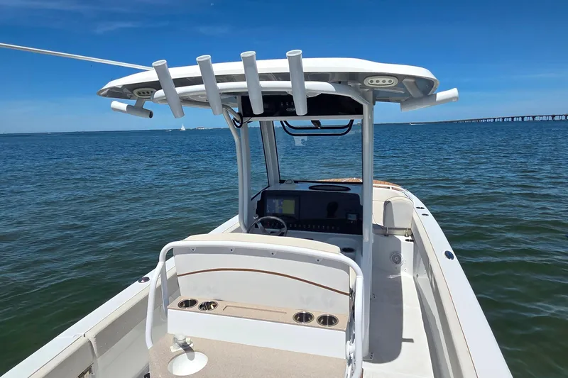 Slide: The Image of 2021 Sea Hunt Escape 27 boat on calm water, featuring a sleek console and rod holders. - 2
