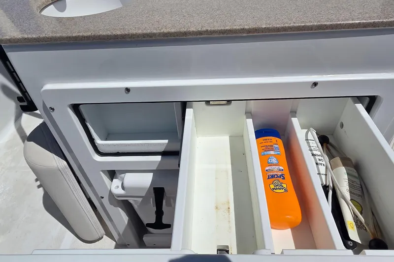 Slide: The Image of Storage compartment on a 2021 Sea Hunt Escape 27 boat with sunscreen and accessories. - 23