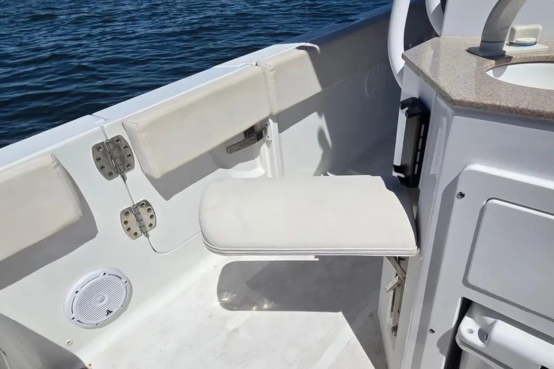 Slide: The Image of 2021 Sea Hunt Escape 27 boat interior with foldable seat and countertop near water. - 24