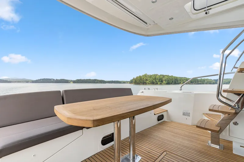 Slide: The Image of Luxurious 2017 Prestige 500 yacht deck with seating, wooden table, and scenic water view. - 29