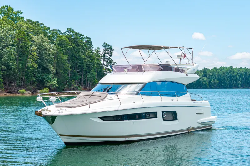 Slide: The Image of Luxurious 2017 Prestige 500 yacht cruising on a serene lake with lush green forest backdrop. - 3