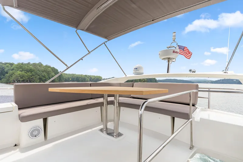 Slide: The Image of Flybridge seating area on 2017 Prestige 500 yacht with table, under a canopy, near scenic waterway. - 31
