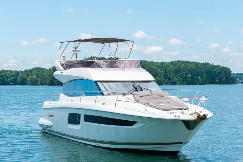 Slide: The Image of Luxury 2017 Prestige 500 yacht cruising on a serene lake with lush green shoreline. - 4