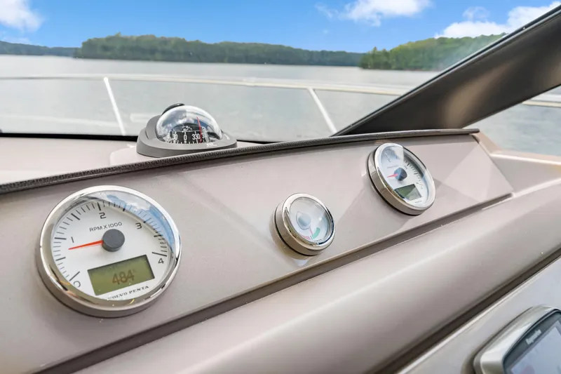 Slide: The Image of Control panel of a 2017 Prestige 500 yacht with gauges and compass, overlooking a serene lake. - 41