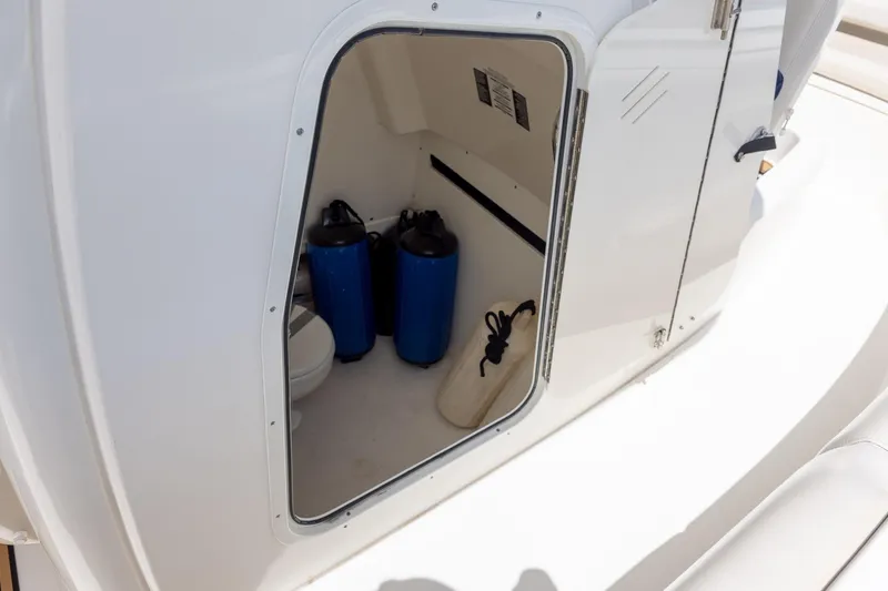 Slide: The Image of 2019 Boston Whaler 280 Outrage storage compartment with blue canisters and white interior. - 14
