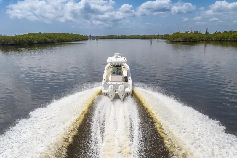 Slide: The Image of 2019 Boston Whaler 280 Outrage cruising on a calm waterway under a blue sky. - 2