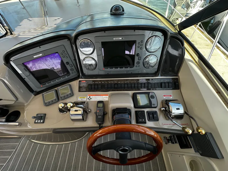 Slide: The Image of The cockpit of a 2006 Sea Ray 380 Sundancer with modern navigation instruments and a wooden steering wheel. - 12