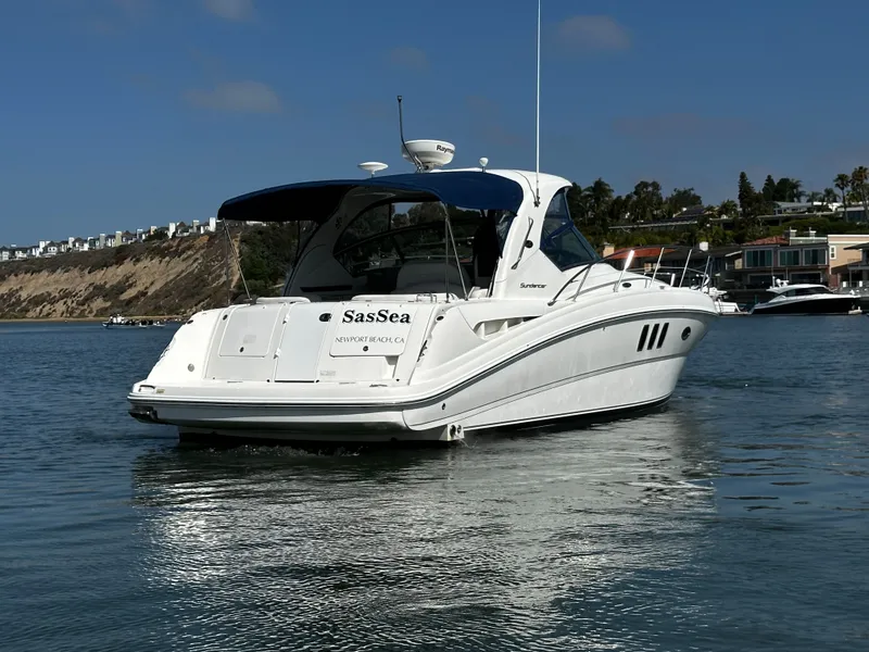 Slide: The Image of A white motorboat with a blue cover floats on calm water in a bay. - 8