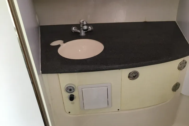 Slide: The Image of Compact bathroom sink in 2013 Everglades 320EX boat, featuring a dark countertop and faucet. - 53