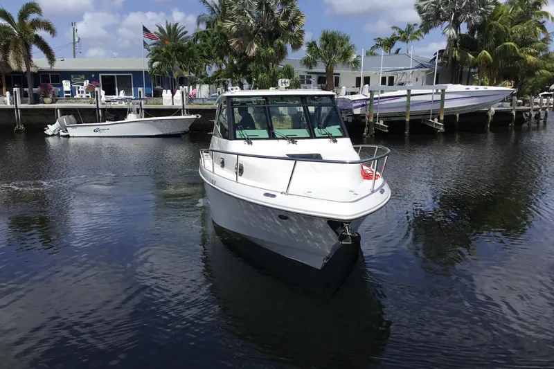 Slide: The Image of 2013 Everglades 320EX boat docked in a scenic marina with palm trees. - 5