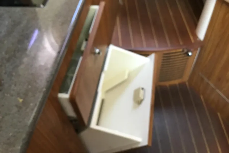Slide: The Image of Interior view of 2013 Everglades 320EX boat with open wooden cabinet and drawer. - 57