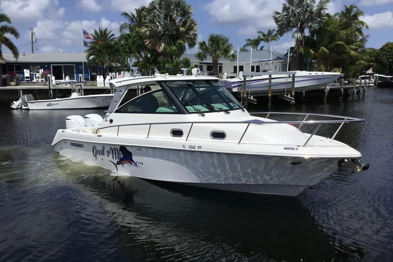 Slide: The Image of 2013 Everglades 320EX boat cruising on a sunny day near a dock with palm trees. - 4