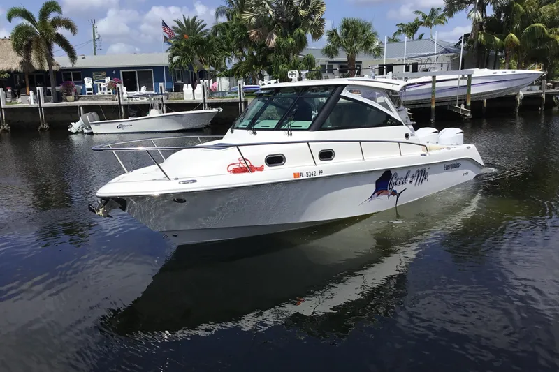 Slide: The Image of 2013 Everglades 320EX boat docked in a scenic marina with palm trees. - 6
