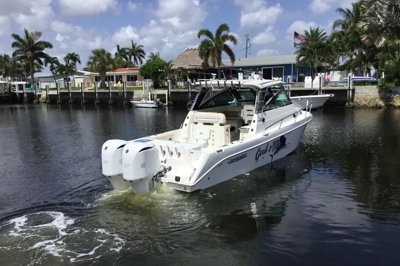 Slide: The Image of 2013 Everglades 320EX boat cruising on a calm waterway with palm trees in the background. - 11