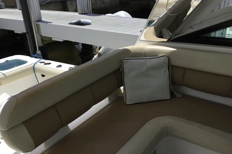 Slide: The Image of 2013 Everglades 320EX boat interior with beige seating and cushion near dock. - 25