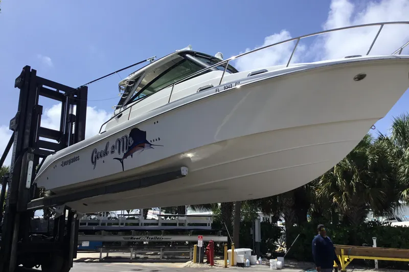 Slide: The Image of 2013 Everglades 320EX boat lifted by forklift, sunny day, palm trees in background. - 62