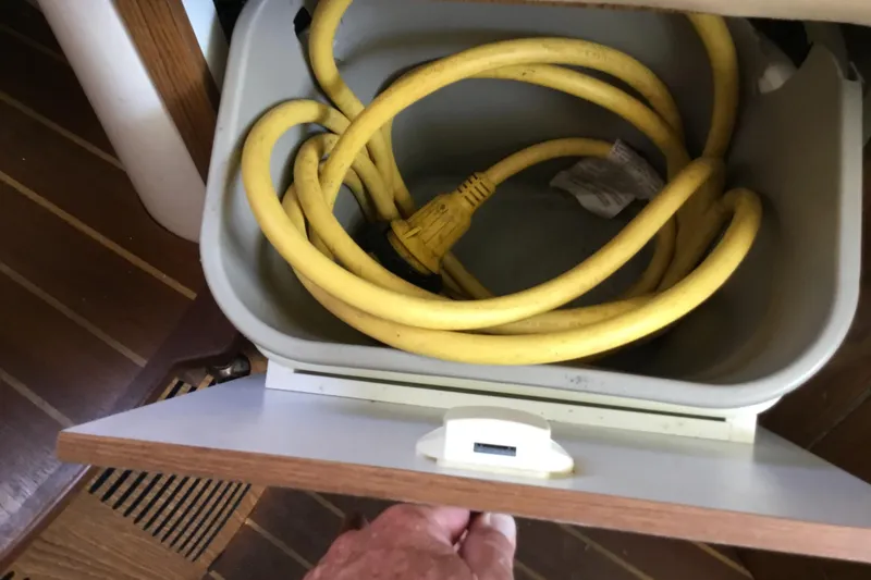 Slide: The Image of Yellow power cable stored in a compartment on a 2013 Everglades 320EX boat. - 58