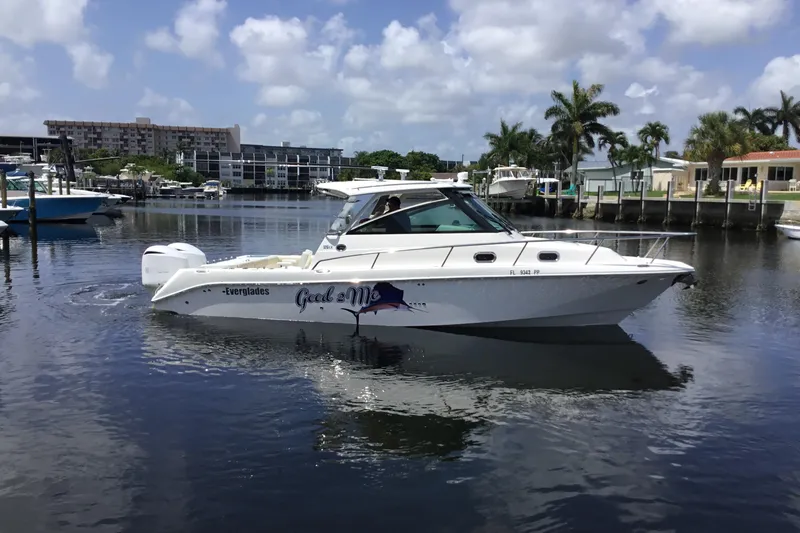 Slide: The Image of 2013 Everglades 320EX boat docked in a marina with palm trees and buildings. - 12