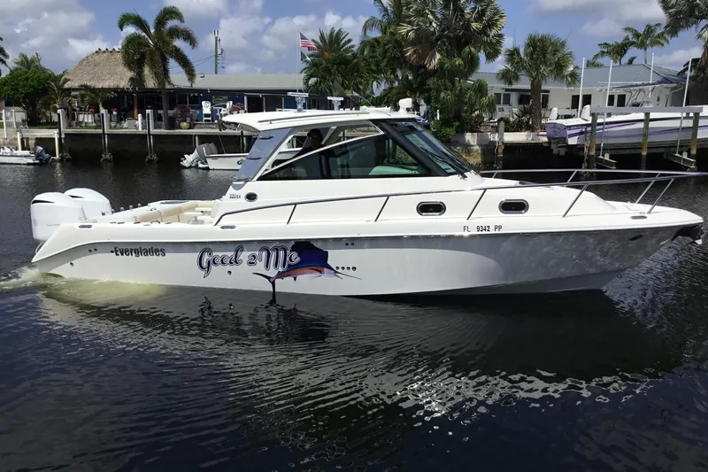 Slide: The Image of 2013 Everglades 320EX boat docked in a scenic marina setting. - 3