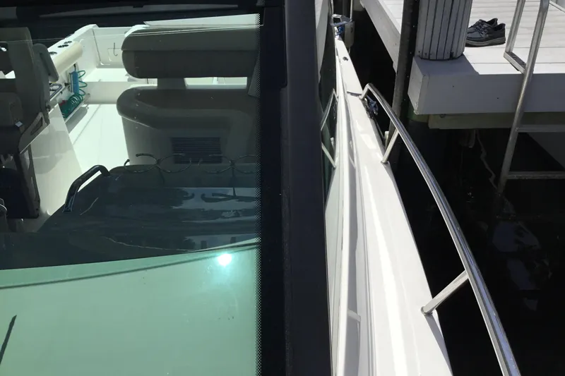Slide: The Image of 2013 Everglades 320EX boat docked, showing interior seating and exterior railing. - 19