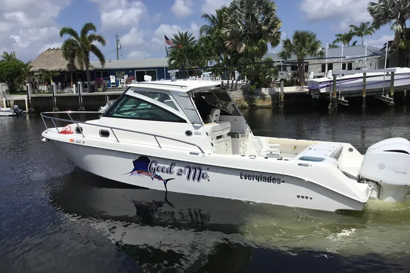Slide: The Image of 2013 Everglades 320EX boat docked near palm trees and waterfront homes. - 8