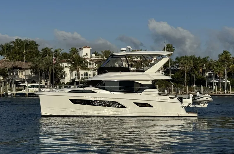 The Image of Aquila 44 yacht, 2022 model, cruising on a sunny day near waterfront homes. - 1