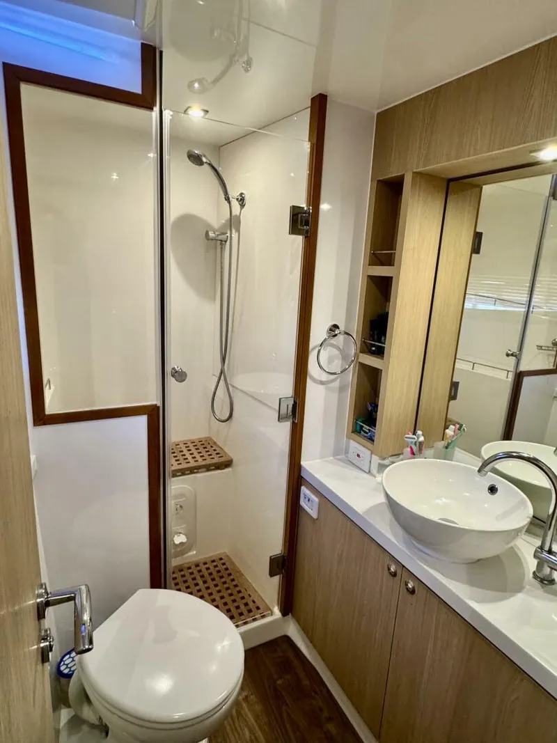 Slide: The Image of Modern bathroom in 2022 Aquila 44 yacht with shower, sink, and wooden accents. - 15