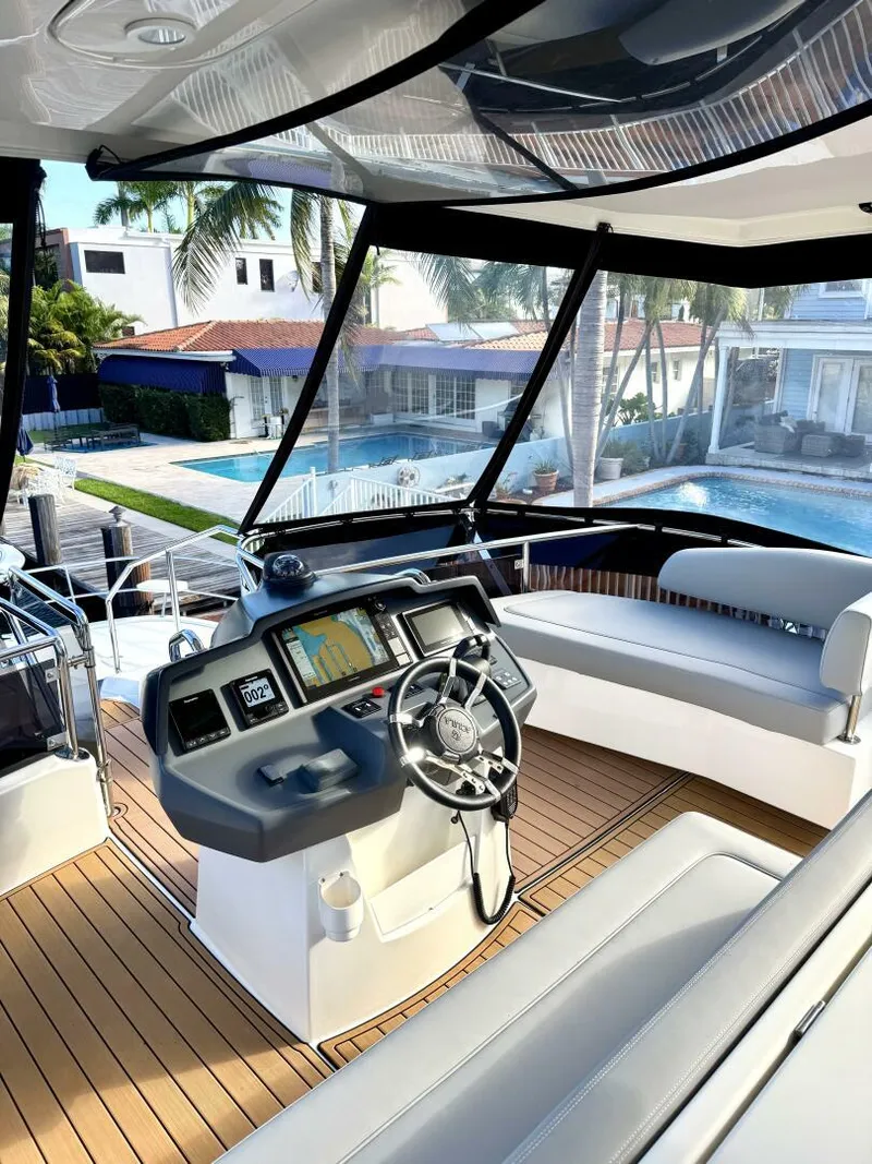 Slide: The Image of Luxury 2022 Aquila 44 yacht interior with modern helm and seating, overlooking waterfront homes. - 23