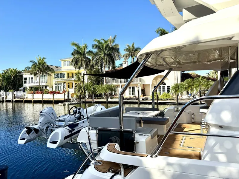 Slide: The Image of Aquila 44 yacht docked by waterfront homes, 2022 model, sunny day, palm trees in background. - 3