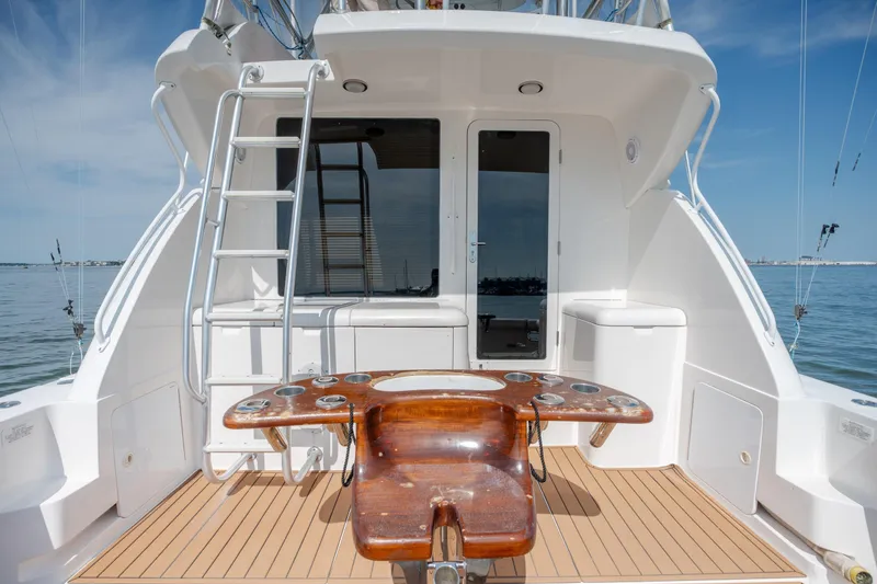 Slide: The Image of 2003 Bertram 390 Convertible yacht deck with fishing chair and ladder, overlooking calm waters. - 51